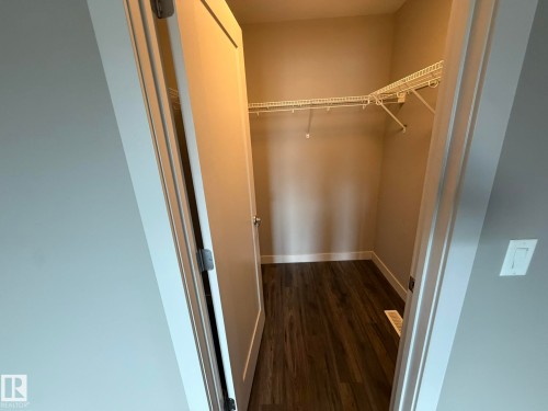Walk-in closet featuring wire shelving, wood-finish flooring, and neutral wall tones - 6821 Evans Wynd, Edmonton, AB 