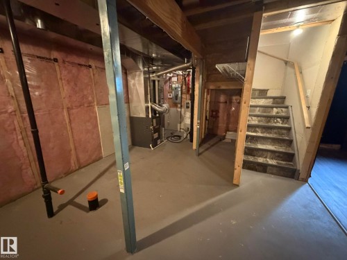 Lower level featuring utility area, painted concrete flooring, and a staircase with wood-finish treads - 6821 Evans Wynd, Edmonton, AB 