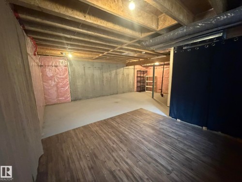 Unfinished basement featuring exposed wood joists and concrete walls - 6821 Evans Wynd, Edmonton, AB 