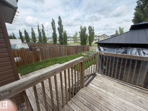 Expansive backyard featuring a wood deck with railings, a level lawn area, and a privacy fence - 6821 Evans Wynd, Edmonton, AB 