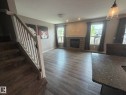 Spacious living area featuring wood-finish flooring, a stone-clad fireplace, and multiple windows - 6821 Evans Wynd, Edmonton, AB 