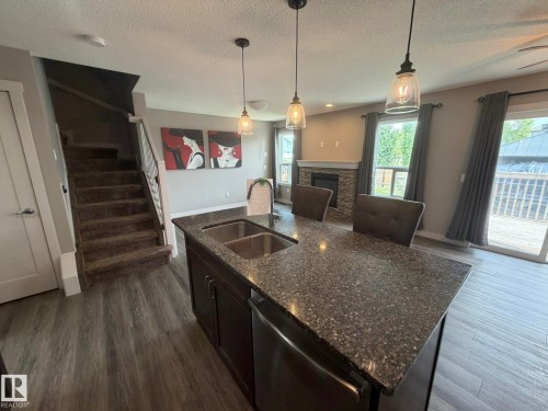 Kitchen island with integrated double basin sink and dark speckled countertop - 6821 Evans Wynd, Edmonton, AB 