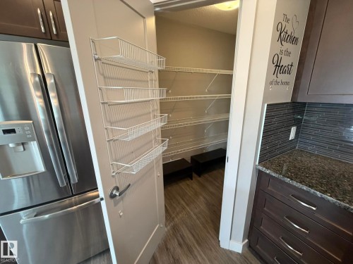 Walk-in pantry featuring wire shelving and wood-finish flooring - 6821 Evans Wynd, Edmonton, AB 