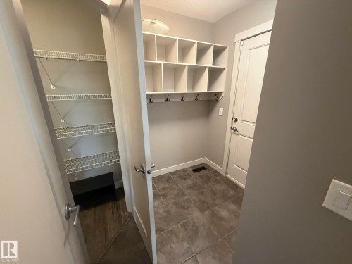 Entryway mudroom featuring built-in cubbies, coat hooks, and durable tile flooring - 6821 Evans Wynd, Edmonton, AB 