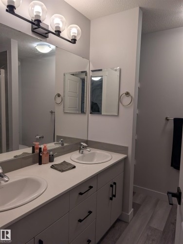 Dual vanity with integrated sinks, light-toned countertops, and contemporary black hardware - 9240 224 Street Nw, Edmonton, AB - Indoor Photo Showing Bathroom