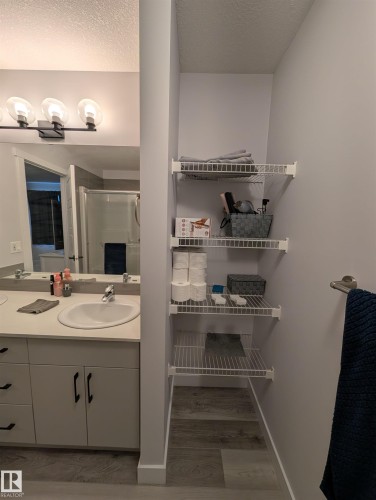 Dual sink vanity with white countertop and integrated sinks, matte black hardware, and wood-finish flooring - 9240 224 Street Nw, Edmonton, AB - Indoor Photo Showing Bathroom