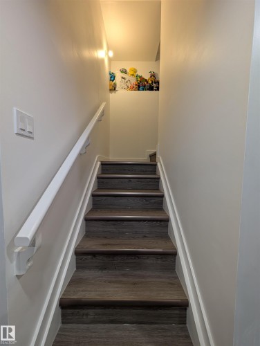 Staircase with wood-finish treads, white risers, and a white wall-mounted handrail - 9240 224 Street Nw, Edmonton, AB - Indoor Photo Showing Other Room