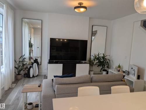 Living area featuring light wood-finish flooring, white walls, and a contemporary flush-mount ceiling light - 9240 224 Street Nw, Edmonton, AB - Indoor