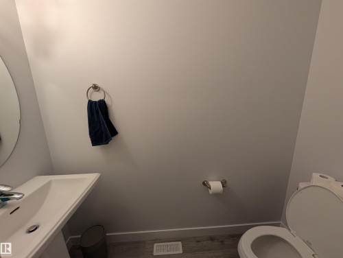 Pedestal sink with chrome faucet, circular wall mirror, and light gray wall paint - 9240 224 Street Nw, Edmonton, AB - Indoor Photo Showing Bathroom