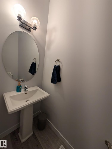 Pedestal sink with chrome faucet, complemented by a round wall-mounted mirror - 9240 224 Street Nw, Edmonton, AB - Indoor Photo Showing Bathroom