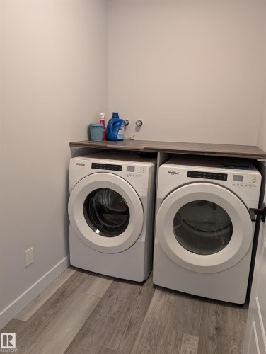 Dedicated laundry area featuring a wood-finish countertop, light gray wall paint, and wood-finish flooring - 9240 224 Street Nw, Edmonton, AB - Indoor Photo Showing Laundry Room