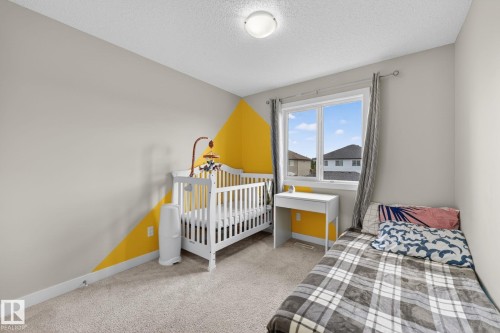 Bedroom with neutral walls featuring a yellow geometric accent - 165 Robinson Drive, Leduc, AB 