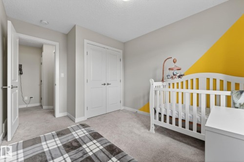 Carpeted room featuring a yellow geometric accent wall - 165 Robinson Drive, Leduc, AB 