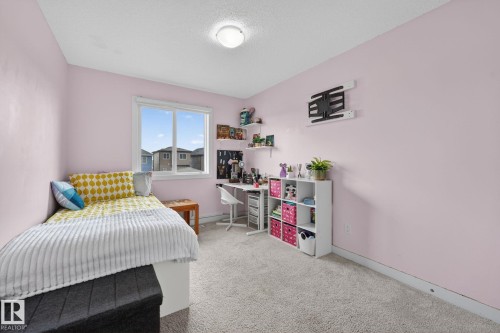 Bedroom featuring a double window, wall-mounted shelving, and carpet flooring - 165 Robinson Drive, Leduc, AB 