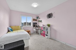 Bedroom featuring a double window, wall-mounted shelving, and carpet flooring - 