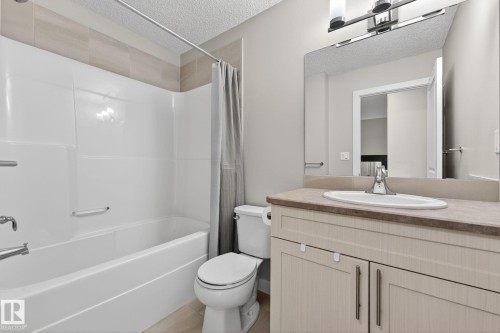 Bathroom featuring a full vanity with an integrated sink, laminate countertop, and wood-finish cabinetry - 165 Robinson Drive, Leduc, AB 