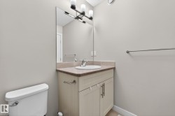 Bathroom featuring a neutral palette, a light wood-finish vanity with dual cabinet doors, a beige countertop, an undermount sink, and a large wall-mounted mirror with overhead lighting - 