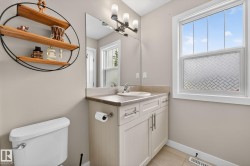Bathroom featuring a single vanity with stone-finish countertop, white cabinetry with brushed nickel hardware, and a framed mirror - 