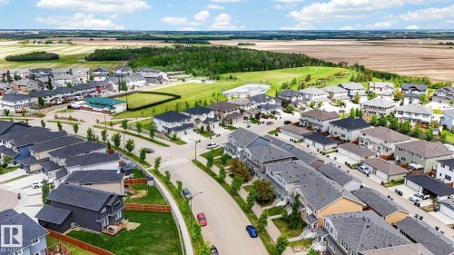 Aerial view of a residential community featuring established homes, paved streets, sidewalks, and manicured green spaces - 165 Robinson Drive, Leduc, AB 