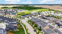 Aerial view of a residential community featuring established homes, paved streets, sidewalks, and manicured green spaces - 
