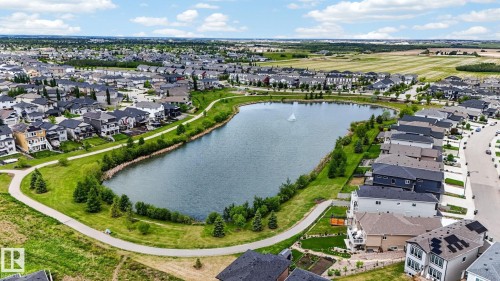 Aerial perspective featuring a central lake with a fountain, surrounded by residential properties and green spaces - 165 Robinson Drive, Leduc, AB 