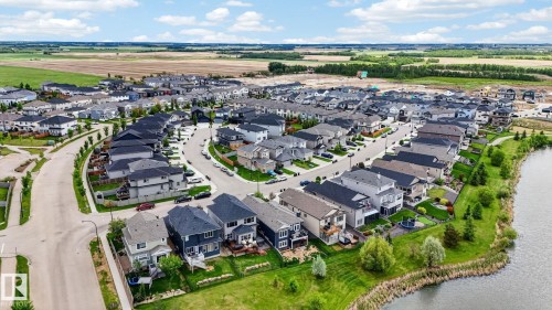 Expansive residential development featuring a curving streetscape, numerous single-family homes, and a prominent waterside green space - 165 Robinson Drive, Leduc, AB 