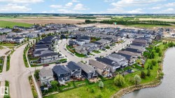 Expansive residential development featuring a curving streetscape, numerous single-family homes, and a prominent waterside green space - 