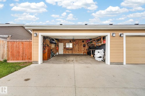 Two-car garage featuring a concrete driveway and light tan siding - 165 Robinson Drive, Leduc, AB 