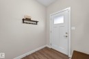 White paneled entry door with frosted glass insert, satin nickel hardware, wood-finish flooring, and light neutral wall paint - 165 Robinson Drive, Leduc, AB 