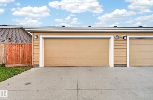 Two-car garage featuring panel-style doors, horizontal siding, and concrete driveway - 165 Robinson Drive, Leduc, AB 