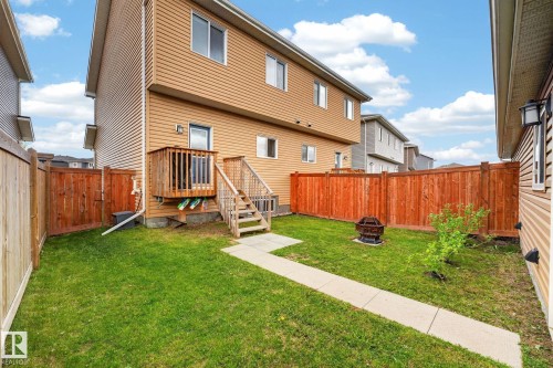 Backyard space featuring a wooden privacy fence, a wooden deck with stairs, a concrete walkway, and a green lawn - 165 Robinson Drive, Leduc, AB 
