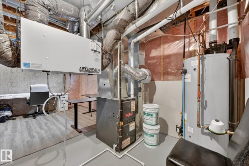 Utility room featuring a water heater, furnace, and exposed ceiling ductwork - 165 Robinson Drive, Leduc, AB 
