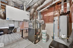 Utility room featuring a water heater, furnace, and exposed ceiling ductwork - 