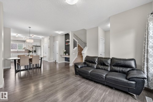 Open-concept living area featuring wood-finish flooring, recessed lighting, a modern chandelier, and light-toned walls - 165 Robinson Drive, Leduc, AB 