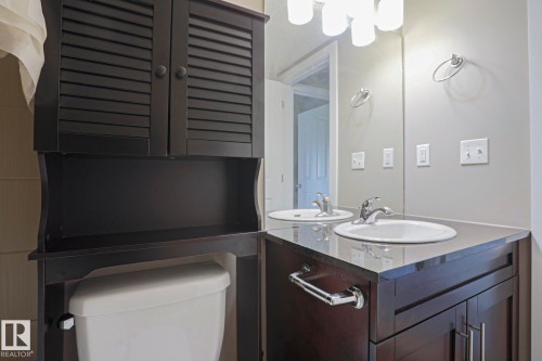 Dual vanity with undermount sinks, a dark countertop, and dark wood-finish cabinetry - 405 11804 22 Avenue Sw, Edmonton, AB 