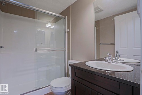 Bathroom featuring a dark wood-finish vanity with an undermount sink and a dark stone-finish countertop - 405 11804 22 Avenue Sw, Edmonton, AB 
