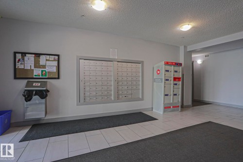 Building entrance featuring mailboxes, parcel lockers, and a bulletin board - 405 11804 22 Avenue Sw, Edmonton, AB 