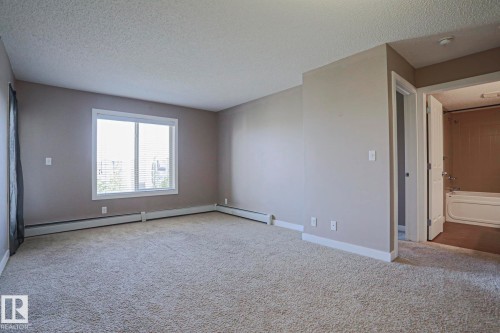 Spacious room featuring neutral carpeting and light-toned walls - 405 11804 22 Avenue Sw, Edmonton, AB 