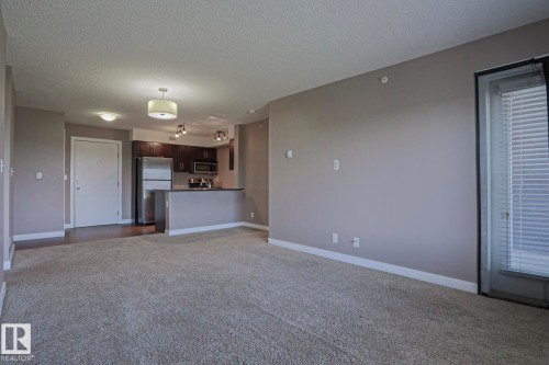 Open-concept living space featuring neutral wall tones and textured carpeting - 405 11804 22 Avenue Sw, Edmonton, AB 