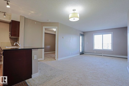 Open concept living space featuring neutral wall tones and plush carpeting - 405 11804 22 Avenue Sw, Edmonton, AB 
