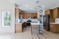 Modern kitchen featuring light wood-finish flooring, recessed lighting, and a contemporary chandelier - 