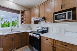 Well-appointed kitchen featuring light wood cabinetry, white countertops, stainless steel appliances, and a tiled backsplash - 