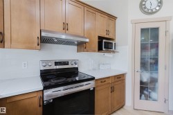 Kitchen featuring wood cabinetry, stainless steel appliances, white subway tile backsplash, and light-toned countertops - 