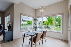Dining area featuring wood-finish flooring, a contemporary spherical chandelier, and multiple large windows with light-colored trim - 