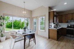 Open-concept dining area featuring wood-finish flooring, a contemporary spherical chandelier, and large windows with transom elements - 
