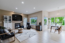 Open-concept living area featuring light wood-finish flooring, recessed lighting, and a prominent fireplace with a tiled surround - 