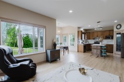 Open-concept living space featuring wood-finish flooring, recessed lighting, and a white countertop island - 