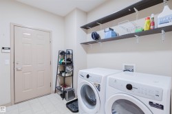 Dedicated laundry space featuring a side-by-side washer and dryer, patterned tile flooring, and two wall-mounted shelving units for additional storage - 
