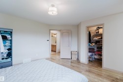 Spacious room featuring wood-finish flooring, a contemporary ceiling light fixture, and neutral wall tones - 