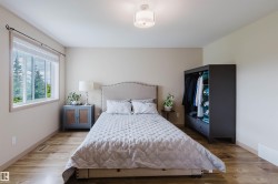 Bedroom featuring wood-finish flooring, a contemporary ceiling light fixture, and a large window with natural light - 